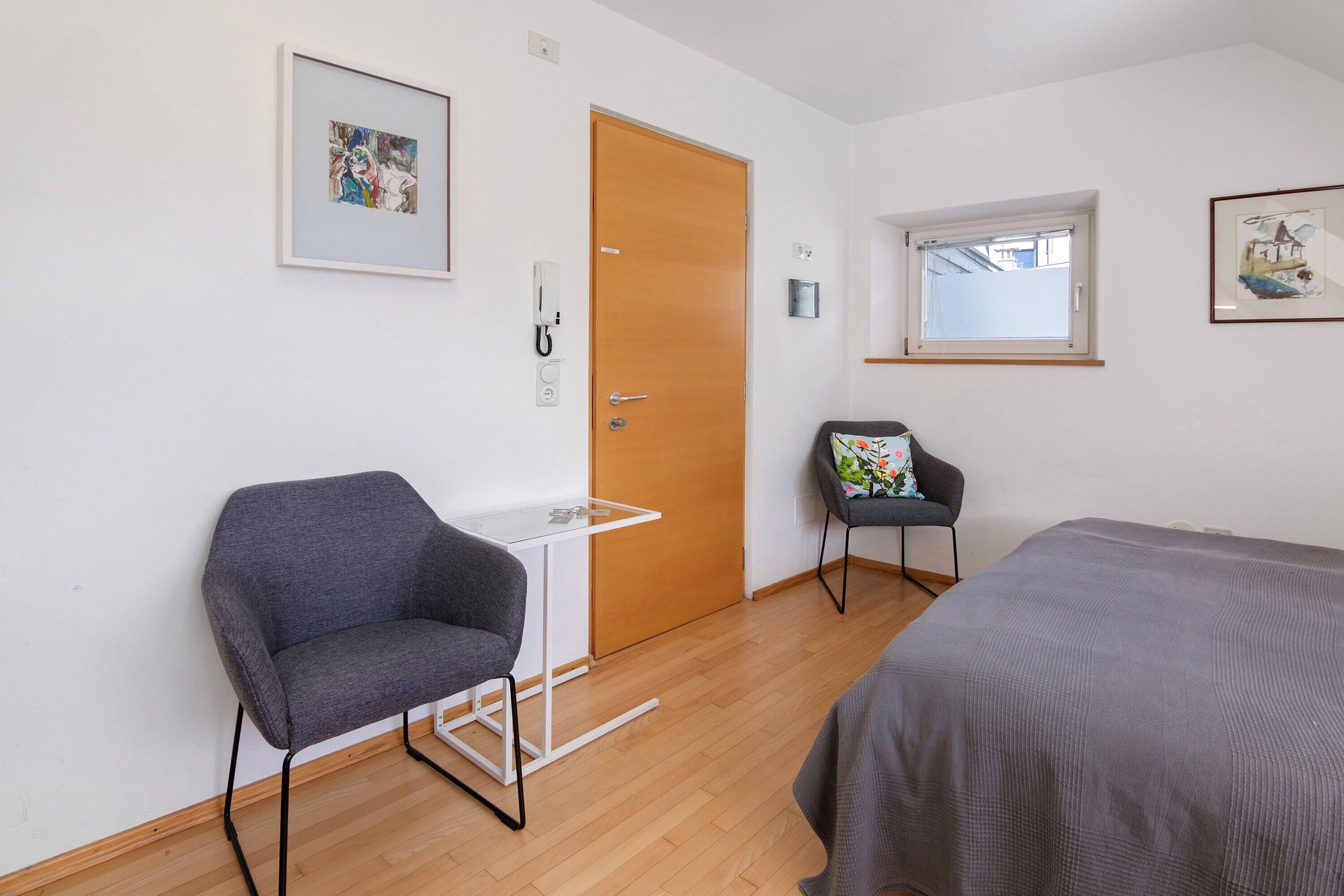 A room with a bed, a desk, a chair, a door, and a window.