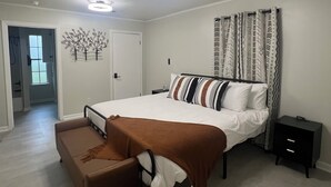 Ein Schlafzimmer mit einem großen Bett, einem Nachttisch, einer Bank und einer Deckenleuchte.