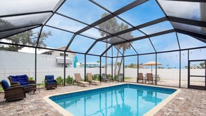 A covered outdoor swimming pool with lounge chairs and a brick patio. - ☀️Steps to Beach | Shared Pool | Awesome Game Room | Beach Villa A☀️ (Fort Myers Beach)