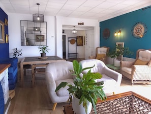 Una sala de estar con un sofá, sillones, una mesa de comedor y una planta en maceta.