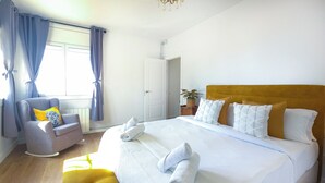 A hotel room with a large bed, a chair, a small table, and a potted plant. - Mikasi Hills by Hello Homes Sitges (Sitges)