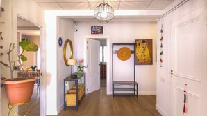 A hallway with a wooden floor, a potted plant, a lamp, and a painting on the wall. - Mikasi Hills by Hello Homes Sitges (Sitges)