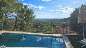 A rectangular swimming pool with a metal railing, surrounded by a grassy area and trees. - Mikasi Hills by Hello Homes Sitges (Sitges)