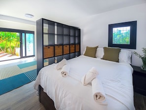 Une chambre moderne avec un grand lit, une armoire intégrée et une vue sur un jardin luxuriant.