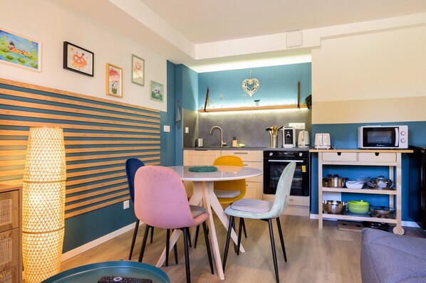 A compact kitchen with a dining area, featuring a microwave, stove, sink, and various kitchen utensils.