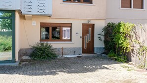 Ein zweistöckiges Gebäude mit befestigtem Eingangsbereich, einer Holztür und einem kleinen Fenster.