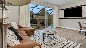 A modern living room with a sofa, a coffee table, and a TV mounted on the wall.