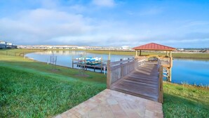 A wooden pier leading to a gazebo by a calm lake with boats docked nearby. - 4BR Storey Lake Home, Heated Pool (Kissimmee)