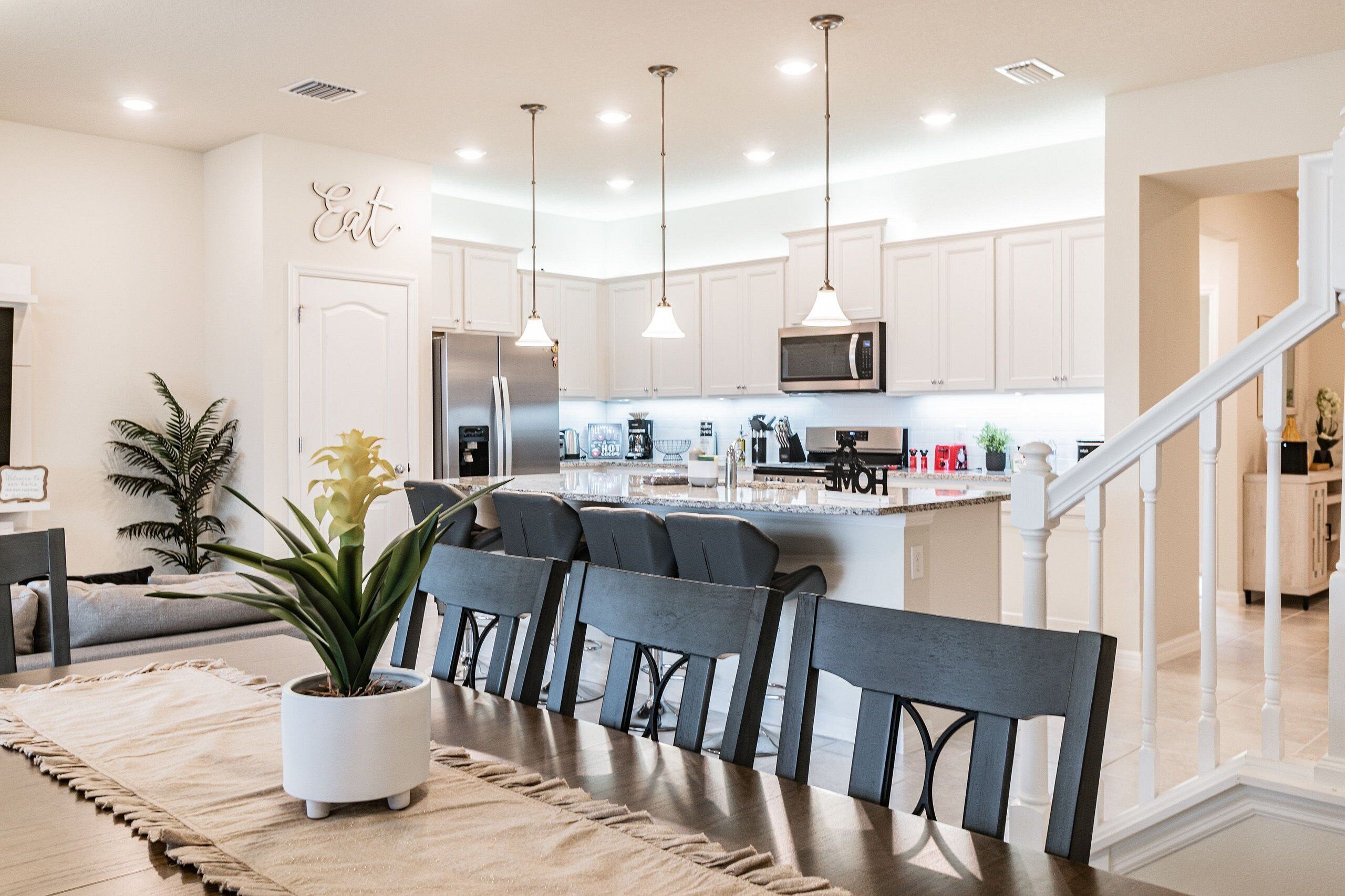 A modern kitchen with white cabinets, stainless steel appliances, and pendant lighting.