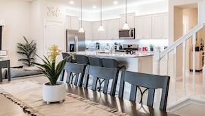 A modern kitchen with white cabinets, stainless steel appliances, and pendant lighting. - 5B/4.5B Pool and Resort (Davenport)