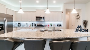 A modern kitchen with granite countertops, stainless steel appliances, and pendant lighting. - 5B/4.5B Pool and Resort (Davenport)