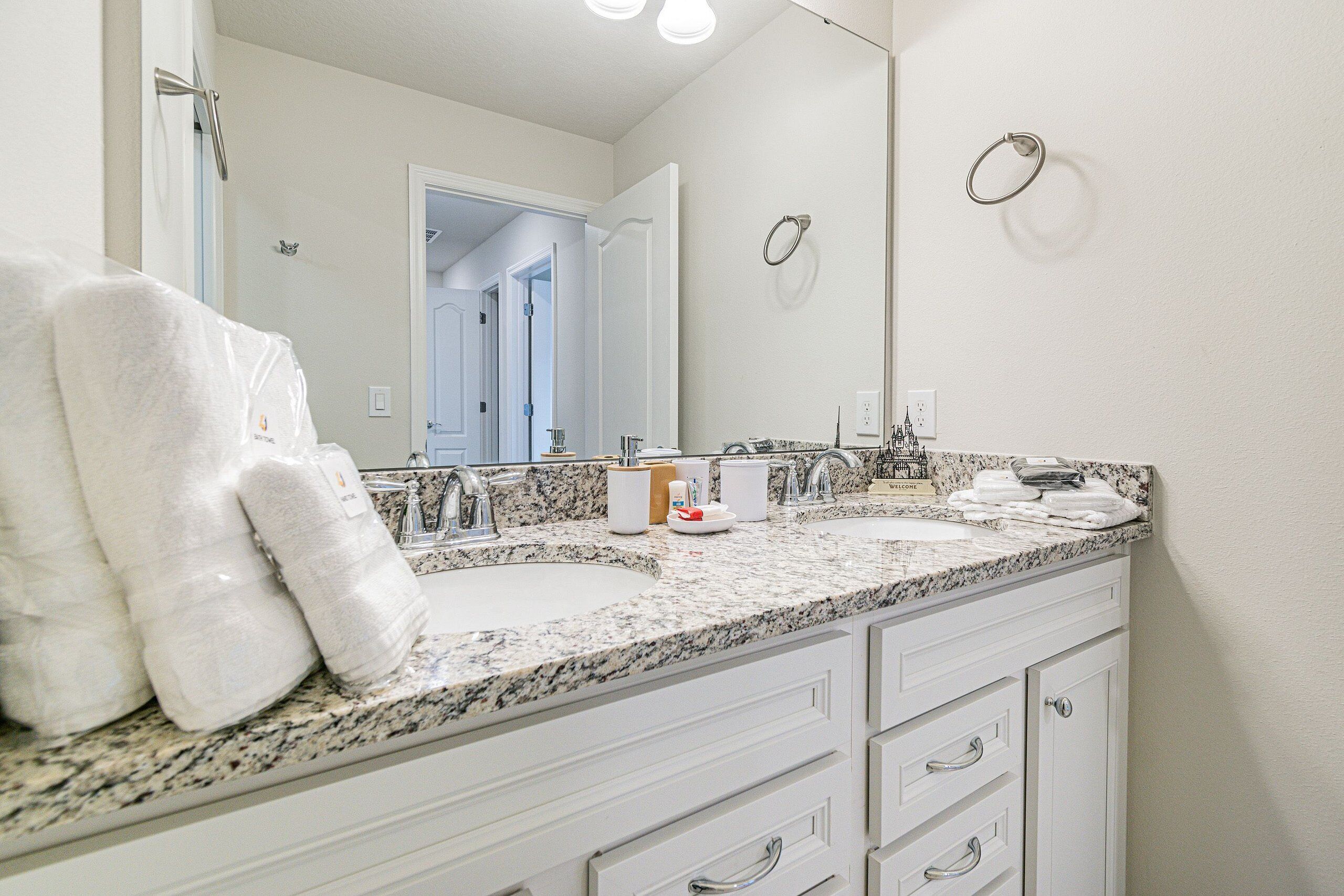 A bathroom with two sinks, a large mirror, and towels on the counter.
