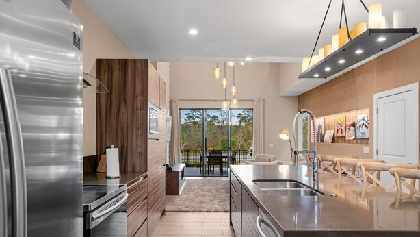 Una cocina moderna con electrodomésticos de acero inoxidable, un muro decorativo de madera y una isla grande con un fregadero.
