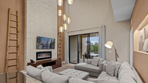 Una sala de estar moderna con chimenea, un sofá grande y un televisor.