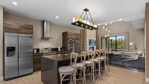 Una cocina moderna con una isla grande, electrodomésticos de acero inoxidable y una zona de bar con taburetes.