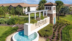 Zona residencial con piscina, un letrero que dice "Windsor" y casas con techos de tejas.