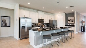 A modern kitchen with white cabinets, stainless steel appliances, and a central island with bar stools.