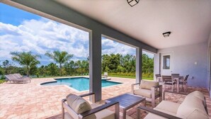 A covered outdoor area with a pool, patio furniture, and a view of the surrounding landscape.