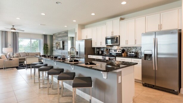 A modern kitchen with a central island, stainless steel appliances, and a bar area.