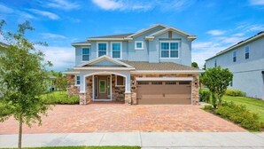 A two-story house with a garage, a front porch, and a brick driveway.