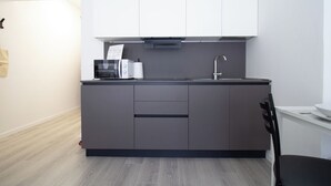 A modern kitchen with grey cabinets, a stainless steel sink, and a black countertop. - Ermes di Colloredo 34 C (Udine)