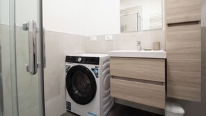 A compact bathroom with a washing machine, a sink, and a mirror. - Ermes di Colloredo 34 C (Udine)
