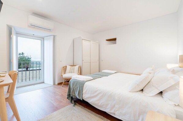 A bedroom with a bed, a chair, a wardrobe, and a balcony.