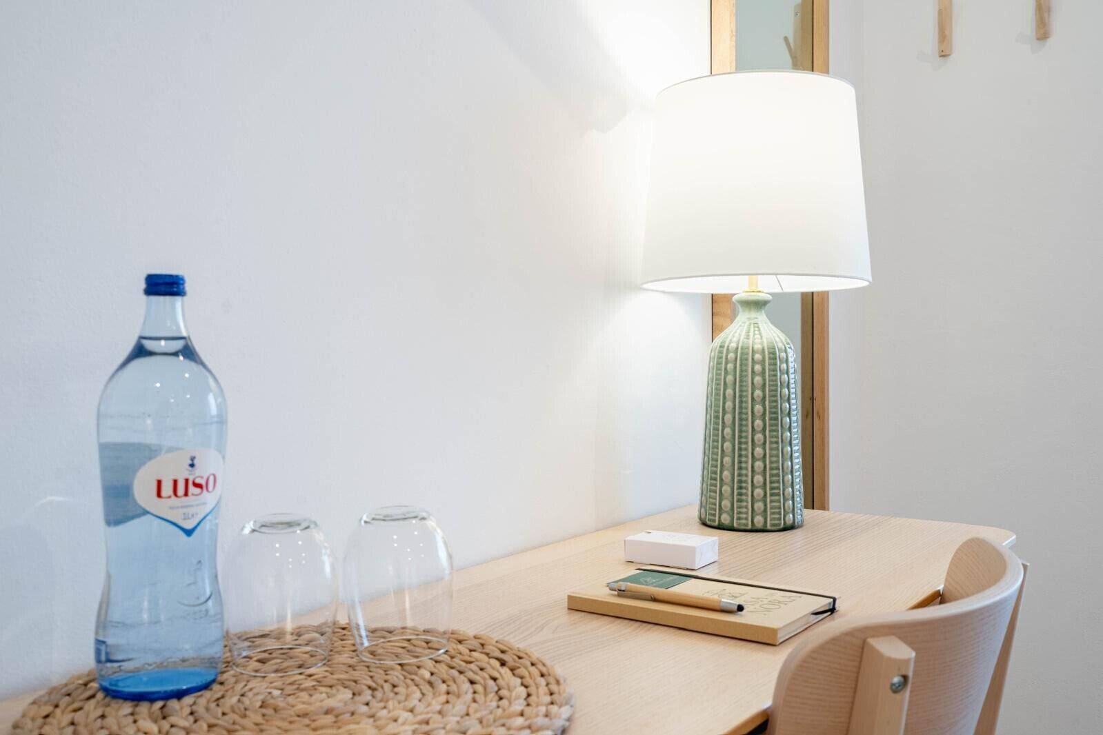 Une table avec une bouteille d’eau, des verres, une lampe et un carnet.