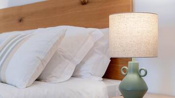 A bed with white bedding and a green lamp on a wooden nightstand.
