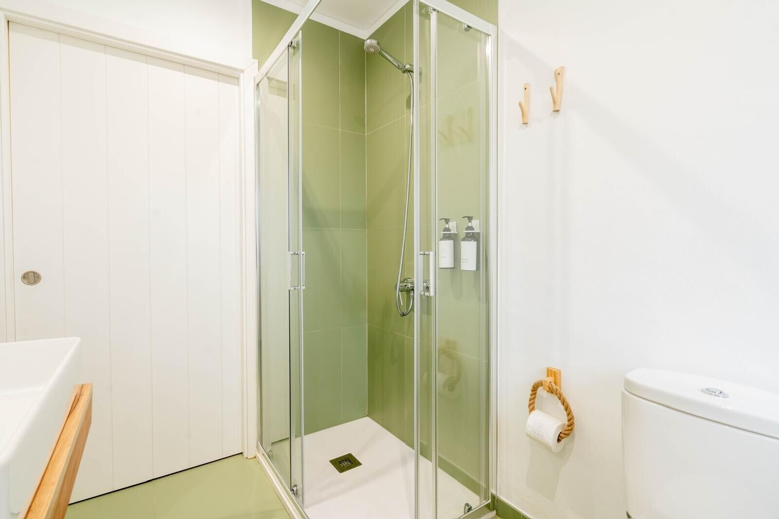 A bathroom with a glass-enclosed shower, a toilet, and a sink.