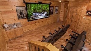 A wooden interior with a large TV screen, wooden cabinets, and a seating area with massage chairs. - All Arrows Pointe To This Vacation Cabin (PIGEON FORGE)