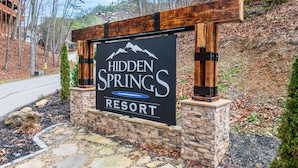 A sign for Hidden Springs Resort with a mountain logo, a pool symbol, and the resort name.