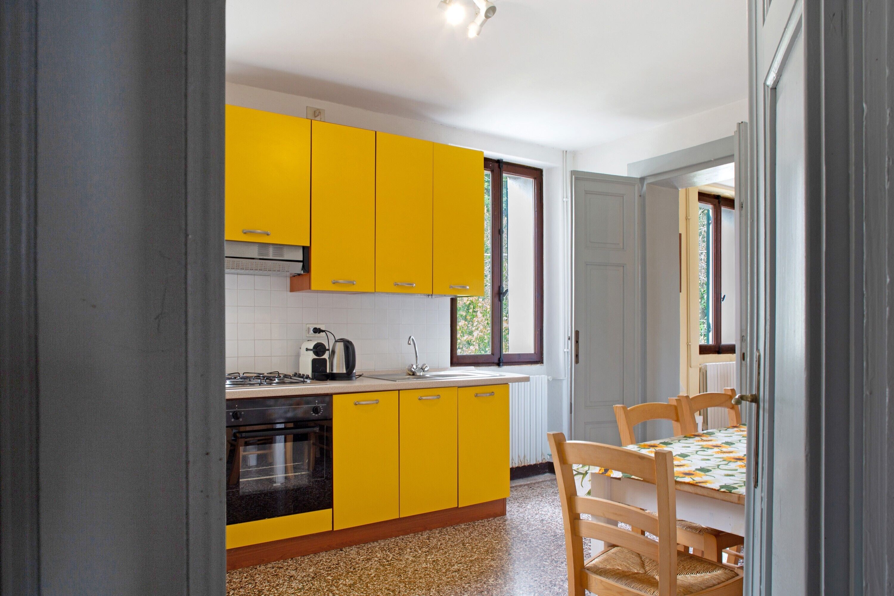 A kitchen with yellow cabinets, a stove, and a dining table with chairs.