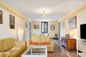 Una sala de estar con sofá, mesa de centro, televisor y lámpara.