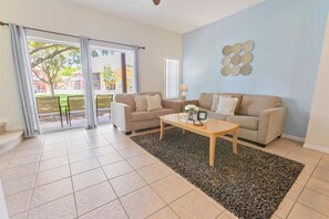 A living room with two beige sofas, a coffee table, and a patterned rug. - CCL8536 Summary:<br>Our (Kissimmee)