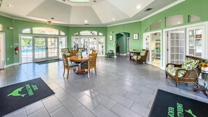 A spacious lobby with a high ceiling, a central dining area, and a seating area with wicker furniture.