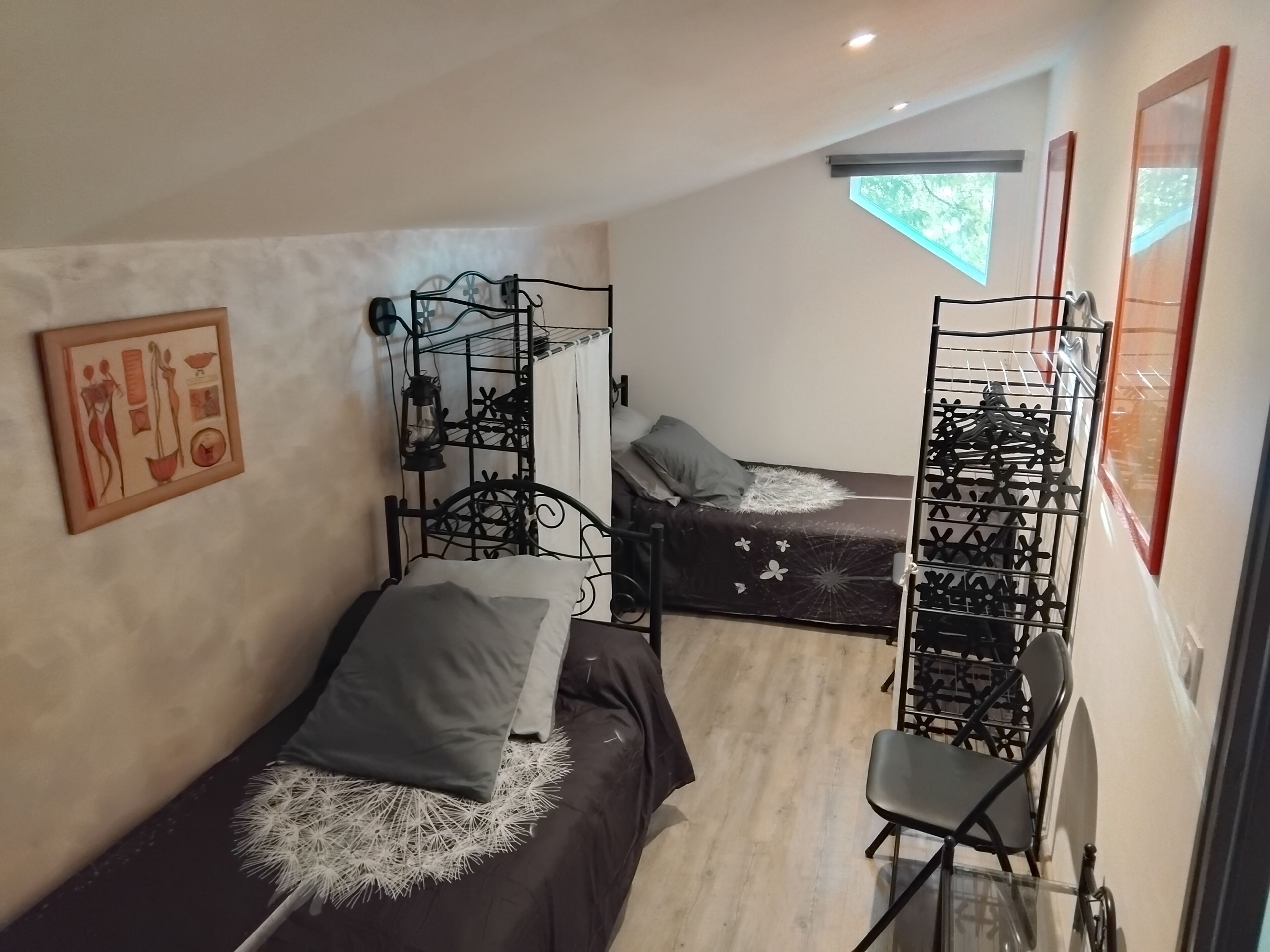A compact room with two beds, a chair, and a metal rack.