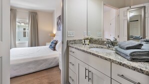 A bedroom with a bed, a bathroom with a sink and mirror, and a view of the outside. - 4BR Lucaya Village Home for Big Groups (Osceola County)
