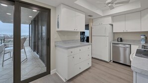 A modern kitchen with white cabinets, a stainless steel refrigerator, and a dishwasher. - ANC903 Summary:<br>The A (Siesta Key)