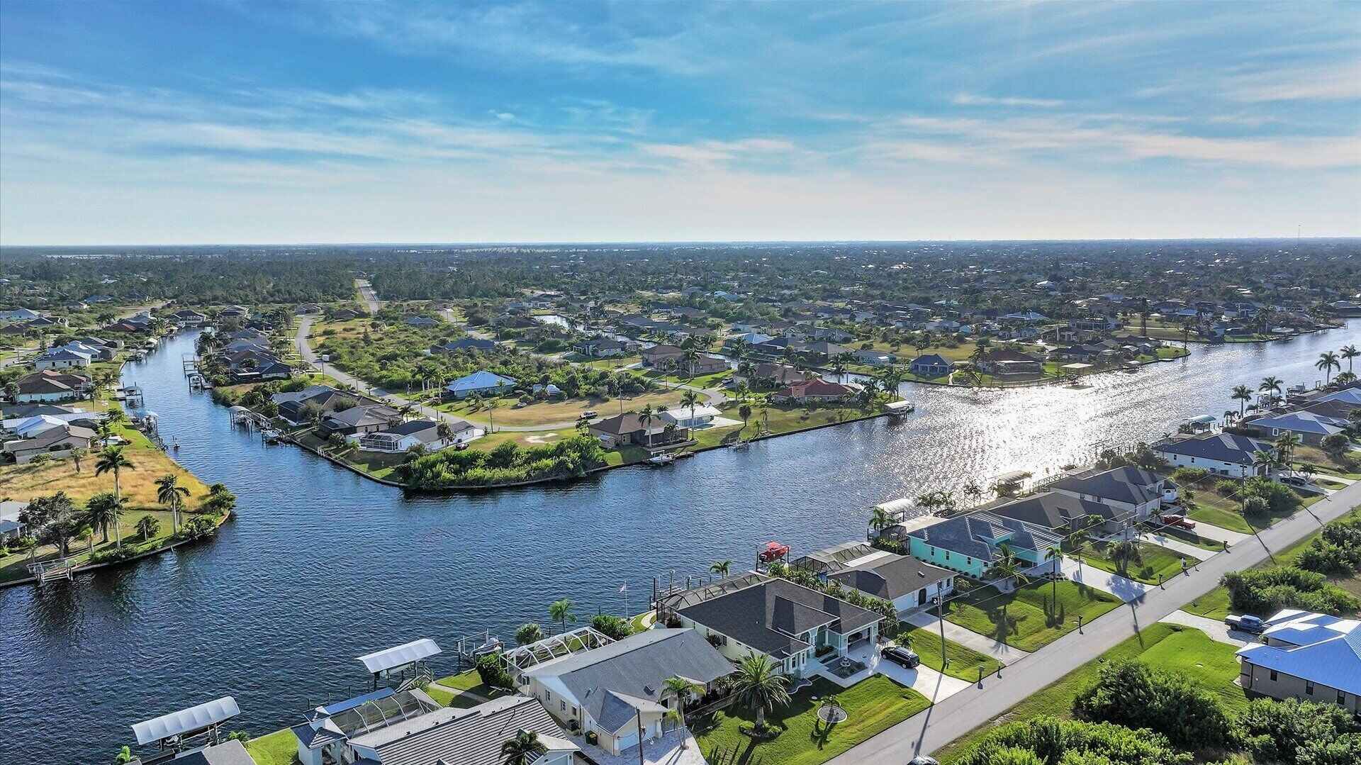 Zona residencial con casas a lo largo de un río, un muelle para embarcaciones y cielo despejado.