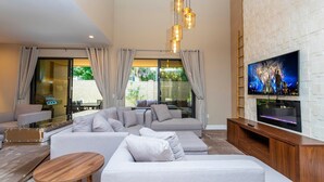 A modern living room with a sectional sofa, a wooden coffee table, and a flat-screen TV mounted on a white brick wall.