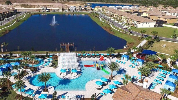 A residential area with a large central swimming pool, a tennis court, and a fountain.