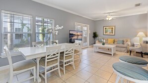 A living room with a dining table, chairs, a sofa, and a TV.