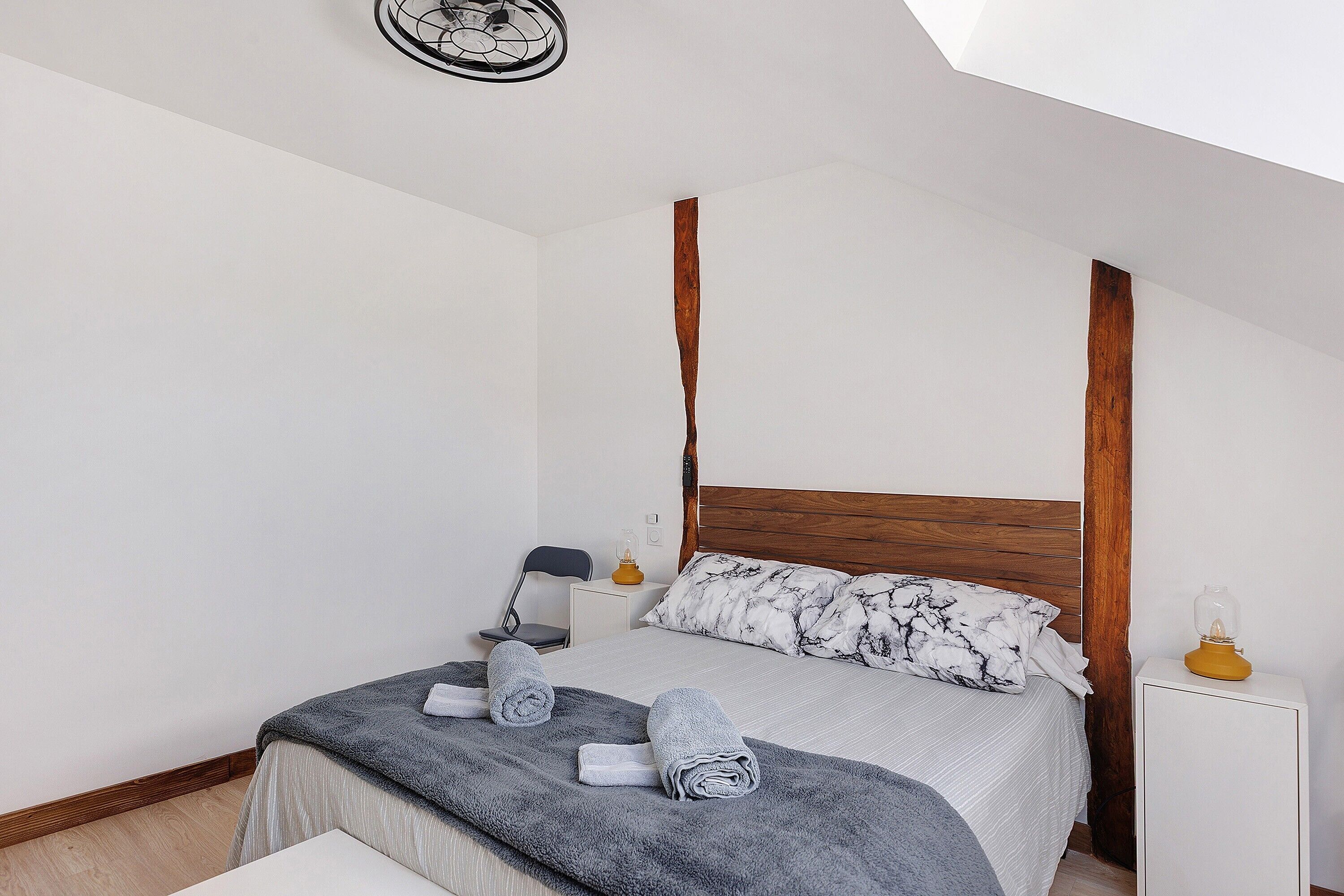 A bedroom with a bed, a bedside table, a chair, and a lamp.
