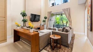 Ein geräumiges Wohnzimmer mit Couch, Holz-Couchtisch und Wand-Fernseher.