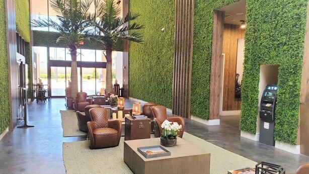 A lobby with a green wall, leather chairs, a coffee table, and a reception desk.