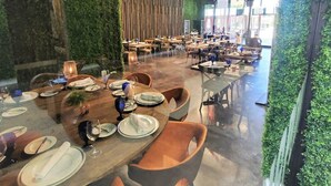 A restaurant with multiple dining tables, green walls, and a modern chandelier.