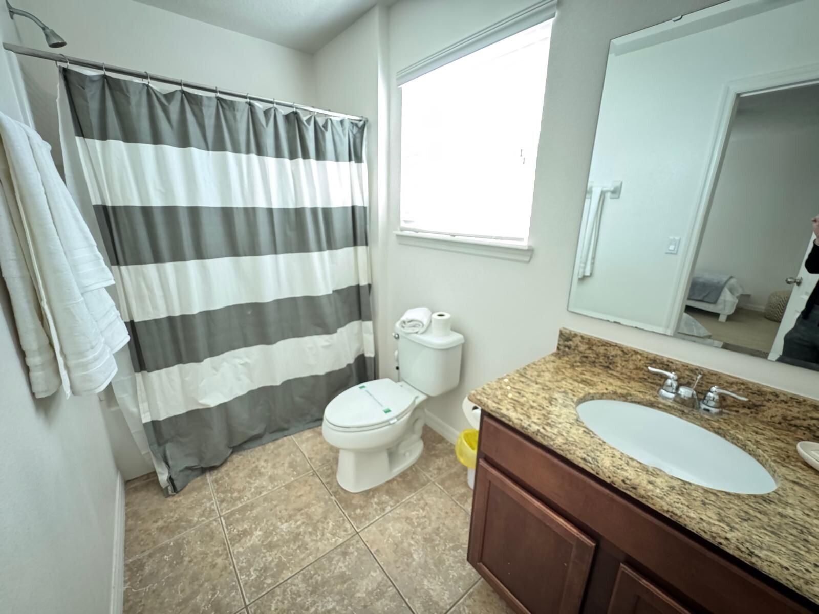 Un baño con cortina de ducha a rayas, inodoro, lavabo y espejo.