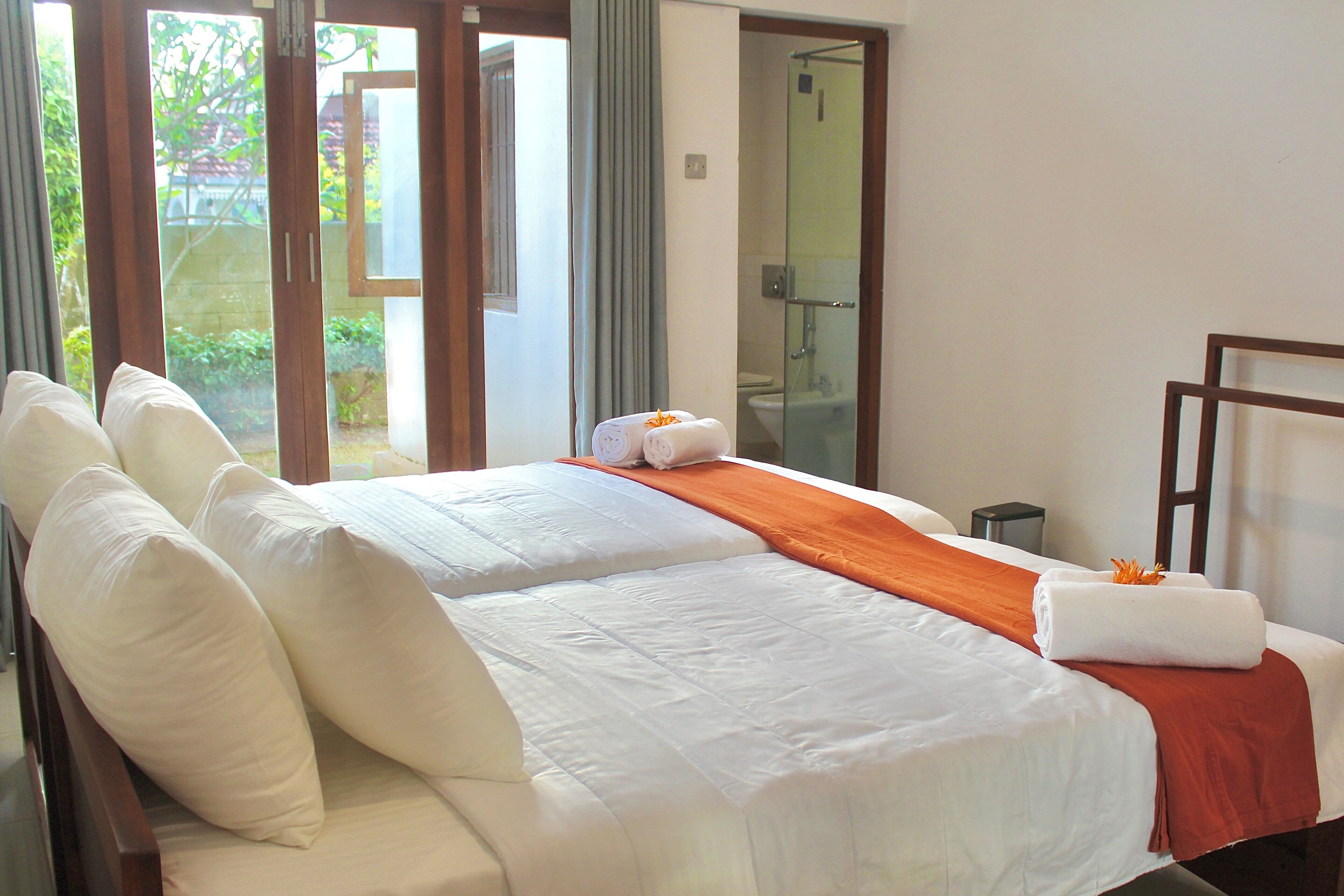 A hotel room with a large bed, a bathroom with a glass shower, and a view of the outside.