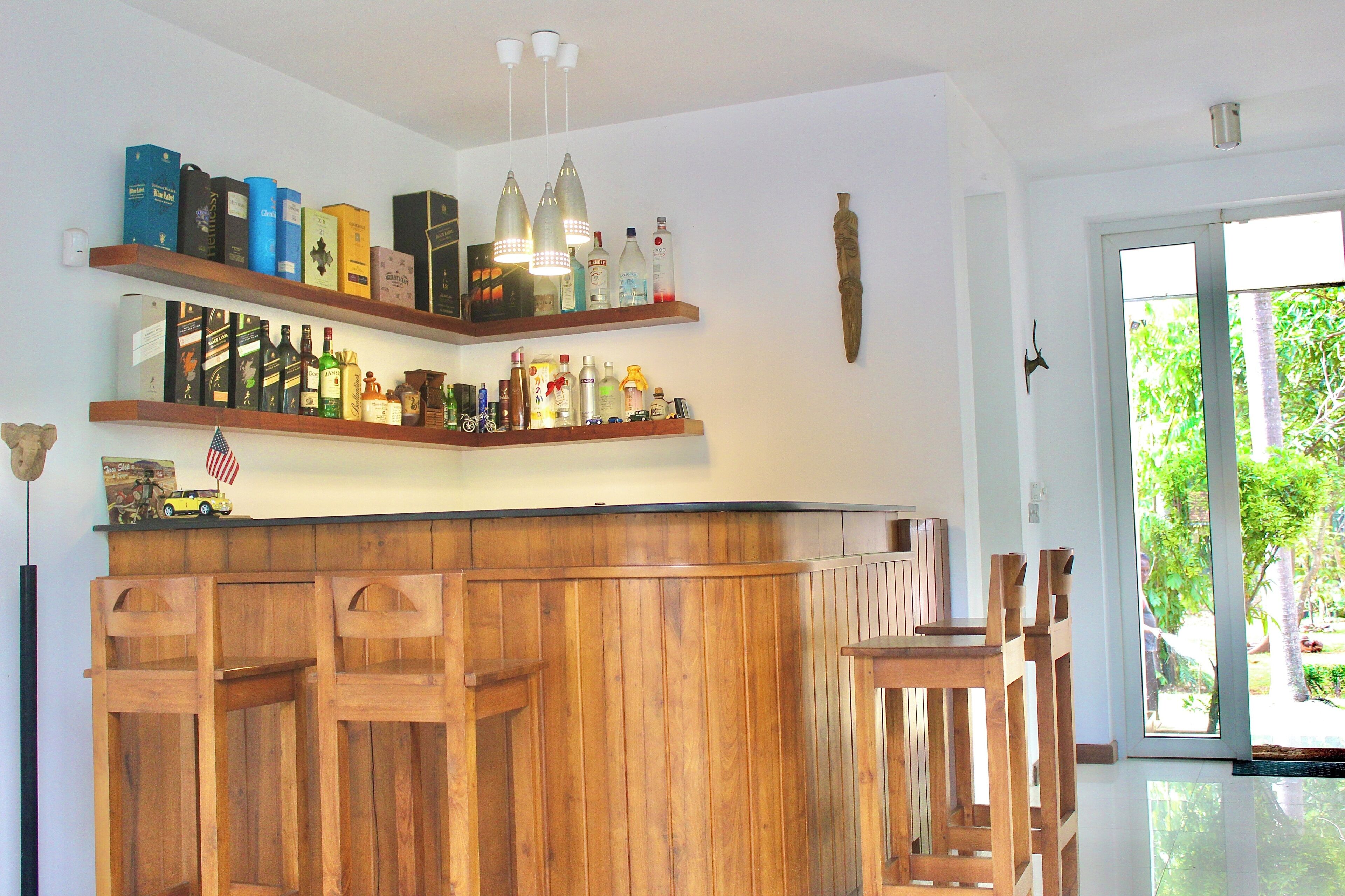 Eine Bar mit Holzböden, die verschiedene Flaschen tragen, einer Holztheke und zwei Barhocker.
